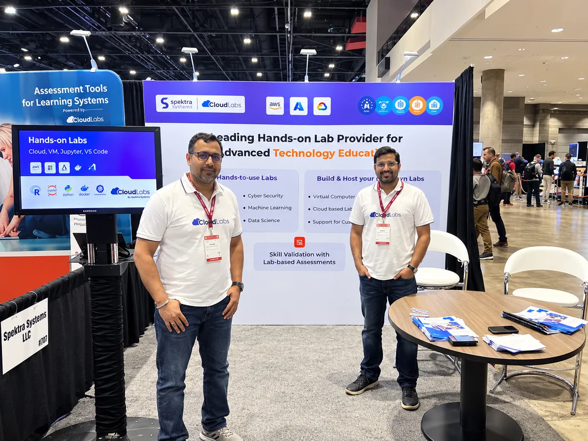 Two CloudLabs team members beside a monitor showing hands-on labs at the Spektra Systems stand